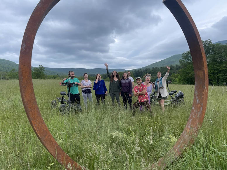 Futurist Network participants gathered inside a large circular sculpture in a green mountain landscape